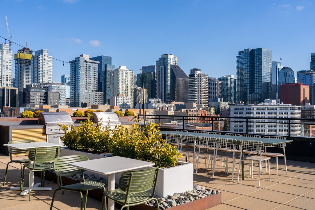 A rooftop patio with a table and chairs overlooking a city skyline.