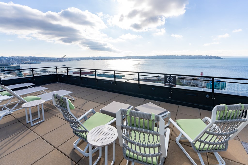 A balcony with chairs and tables overlooking a body of water.