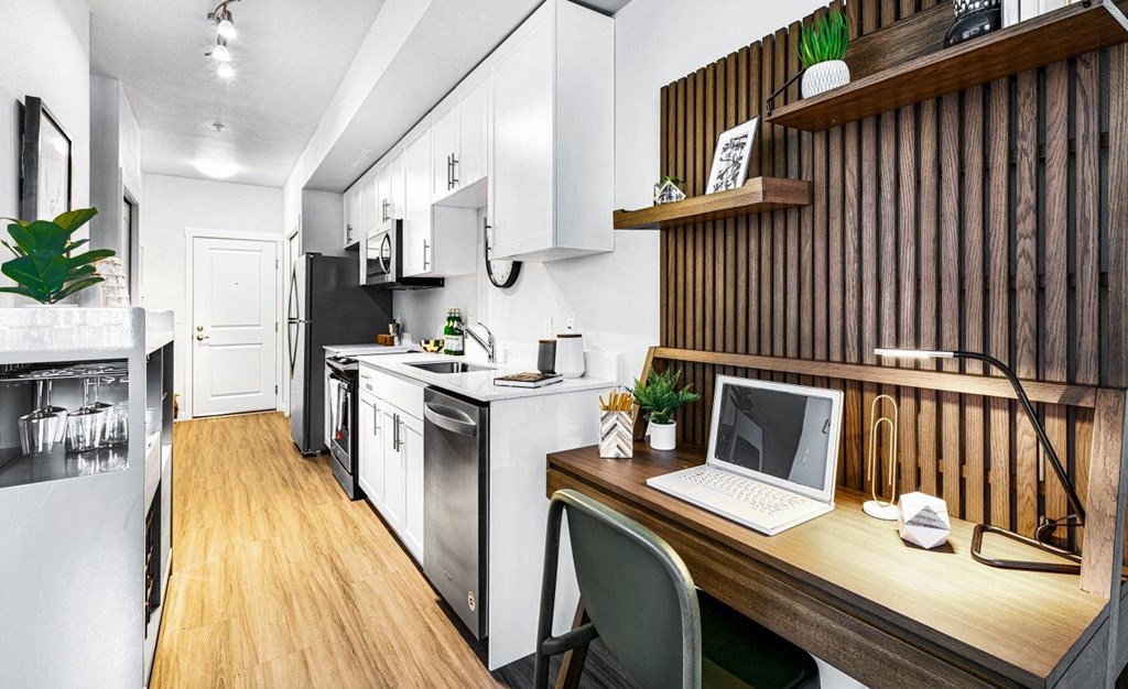 a kitchen with a desk and a laptop on a table