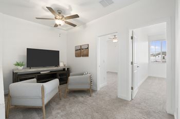 A living room with a television, two chairs, and a ceiling fan.
