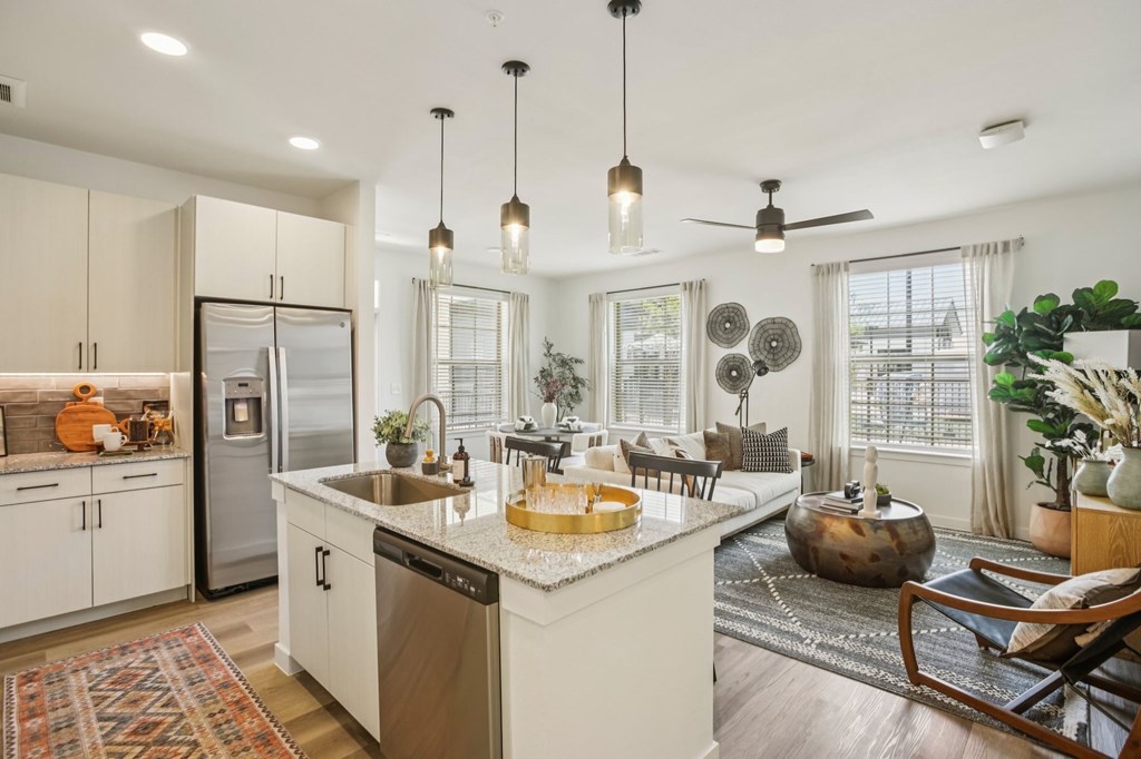 A kitchen with a refrigerator, sink, and a dining table with chairs.