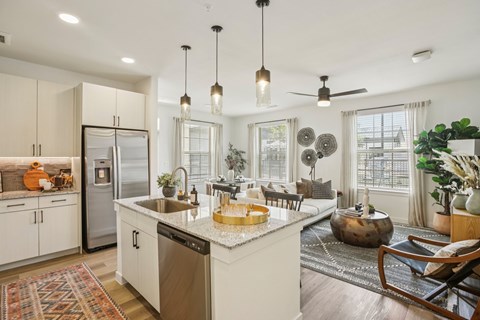 A kitchen with a refrigerator, sink, and a dining table with chairs.
