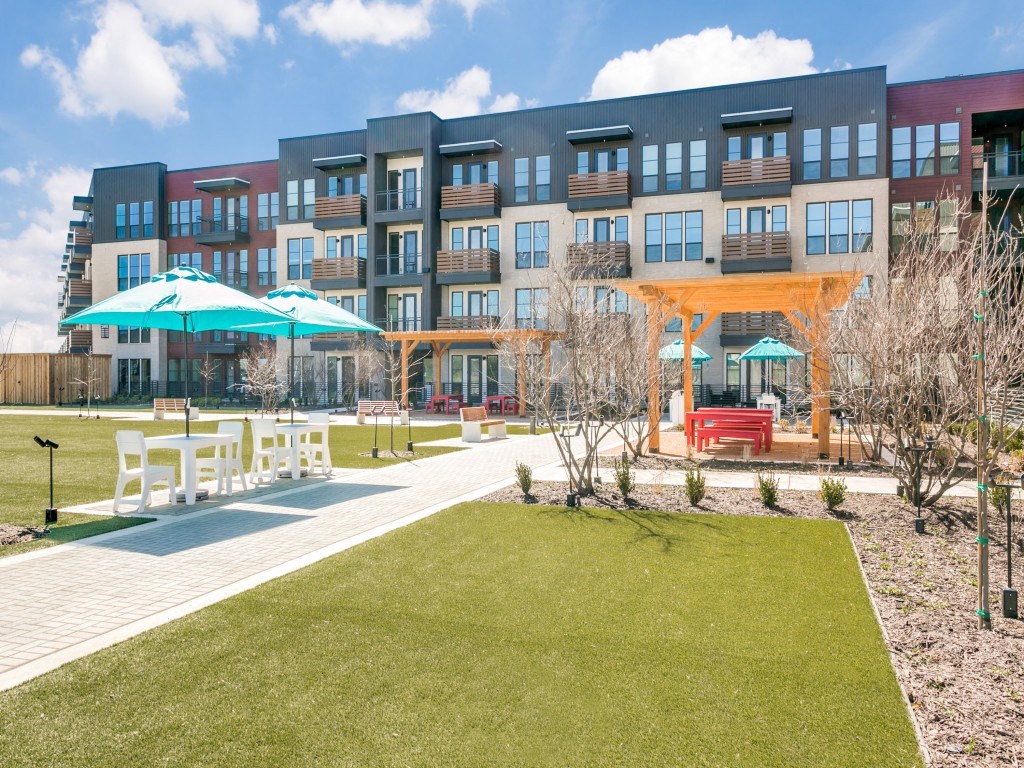 a building with a lawn and umbrellas in front of it
