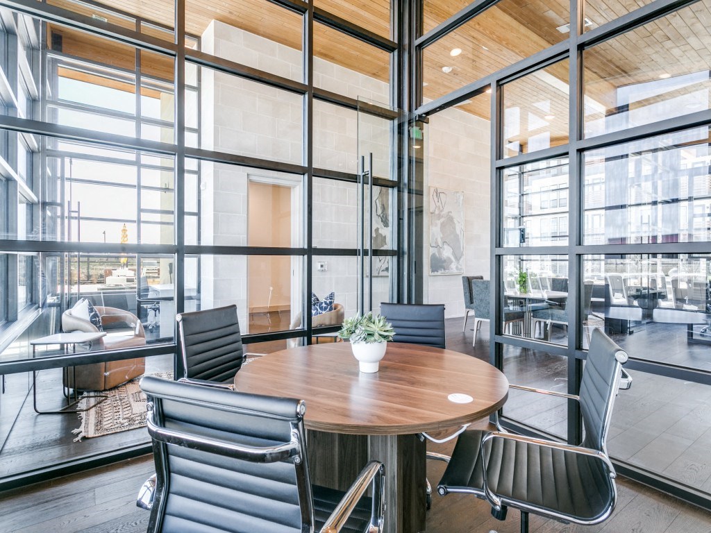 a conference room with glass walls and a wooden table and chairs