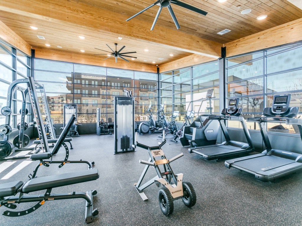 the gym has treadmills and other exercise equipment in the glassed in room
