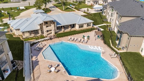 A large swimming pool surrounded by a fence and lounge chairs.