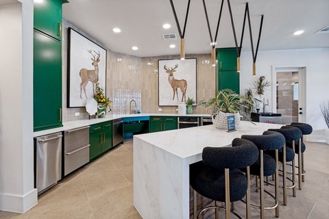 A kitchen with green cabinets and a white island.