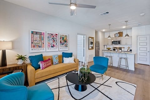 A living room with a yellow couch, blue chairs, and a coffee table.