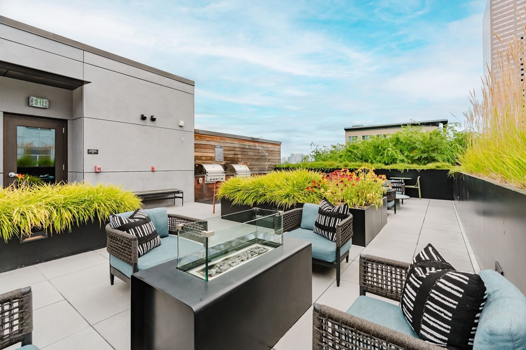 A patio with a table and chairs is surrounded by green plants.