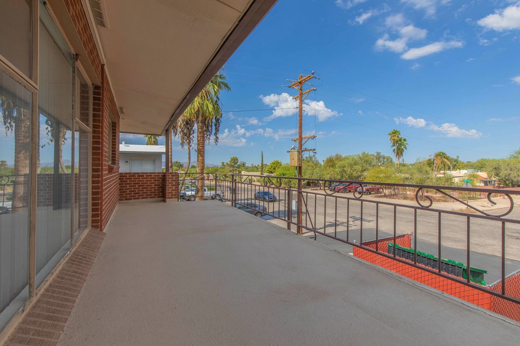 A balcony with a view of a parking lot and palm trees.