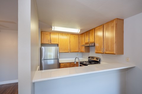 A kitchen with wooden cabinets and a stainless steel refrigerator.