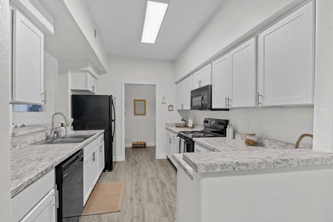 A kitchen with white cabinets and marble countertops.