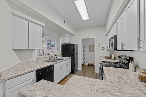 A kitchen with white cabinets and a marble countertop.