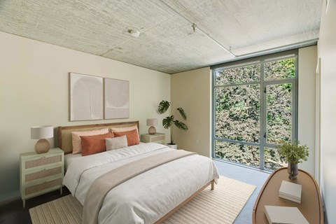 A bedroom with a large bed and a view of trees outside the window.