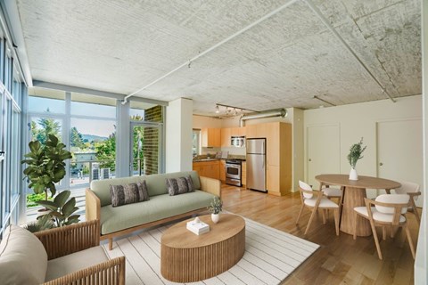 Living room with large windows and wood-style flooring at 2121 Belmont apartments in the Buckman neighborhood in Portland, Oregon.