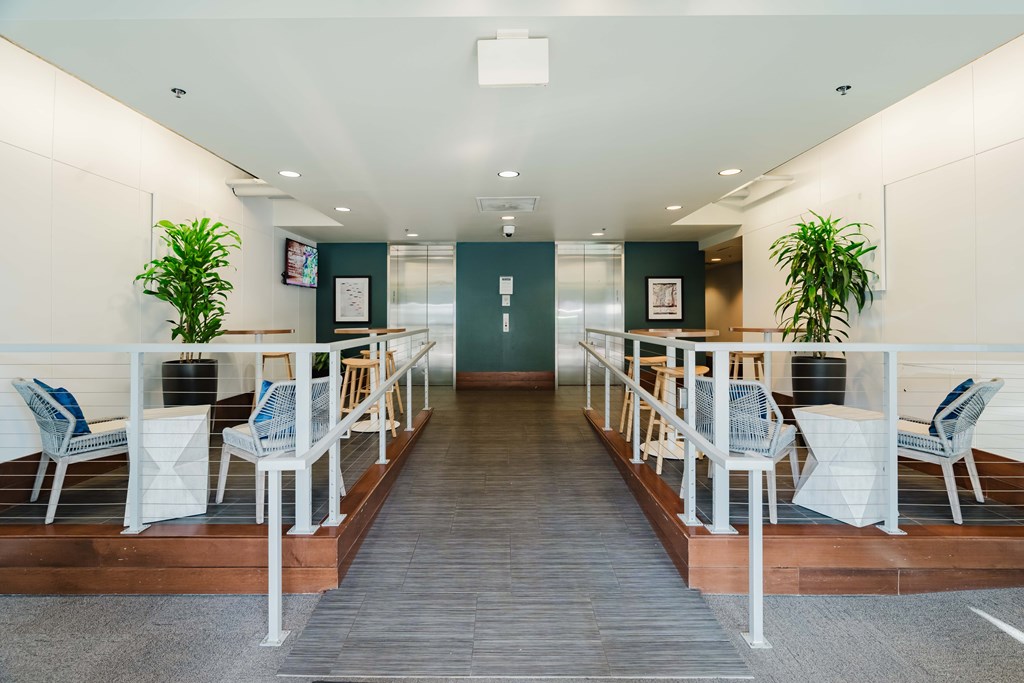 A long hallway with chairs and plants on either side.