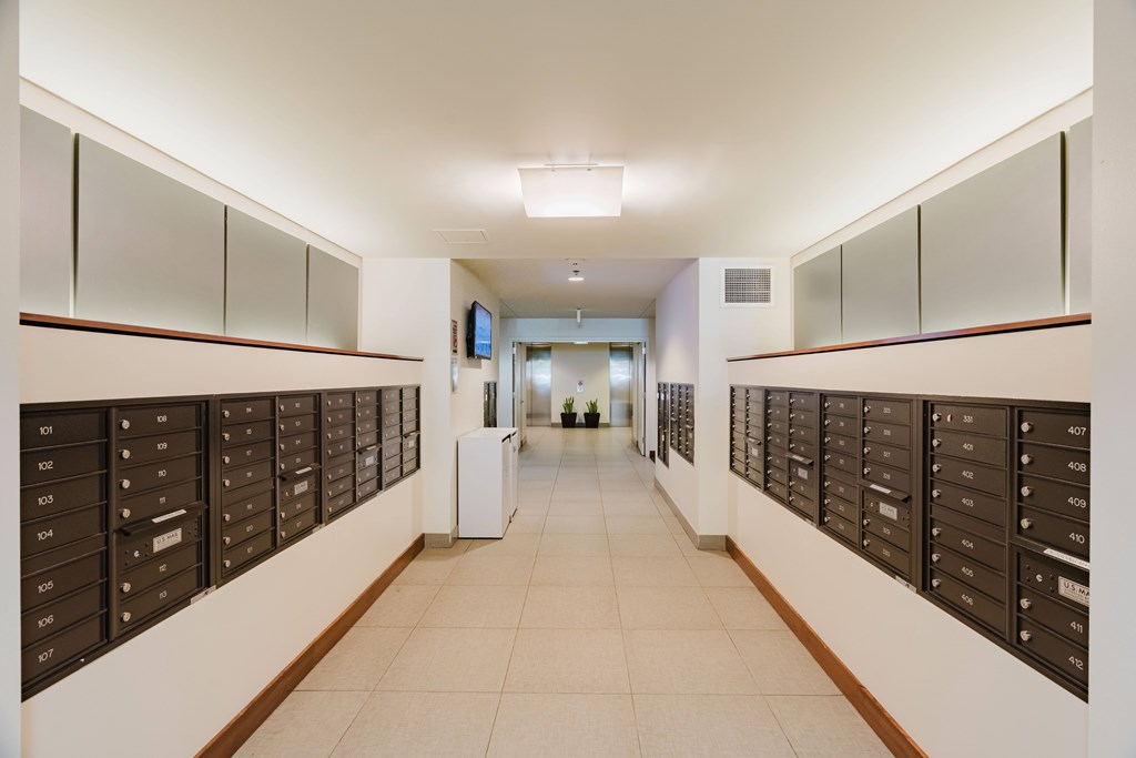 A hallway with mailboxes on the wall and a door at the end.