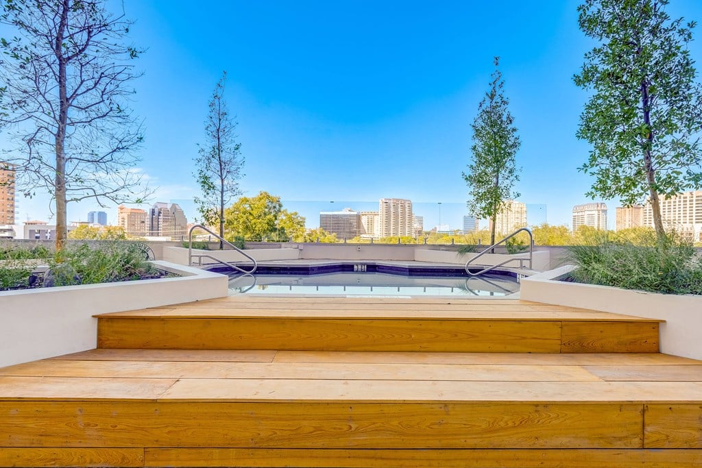 the pool on the roof of a building with a city in the background