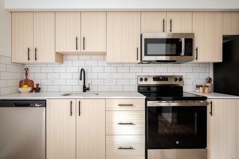 A modern kitchen with wooden cabinets and black appliances.