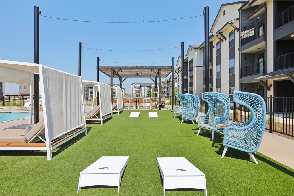 A sunny day at the pool with chairs and a table.