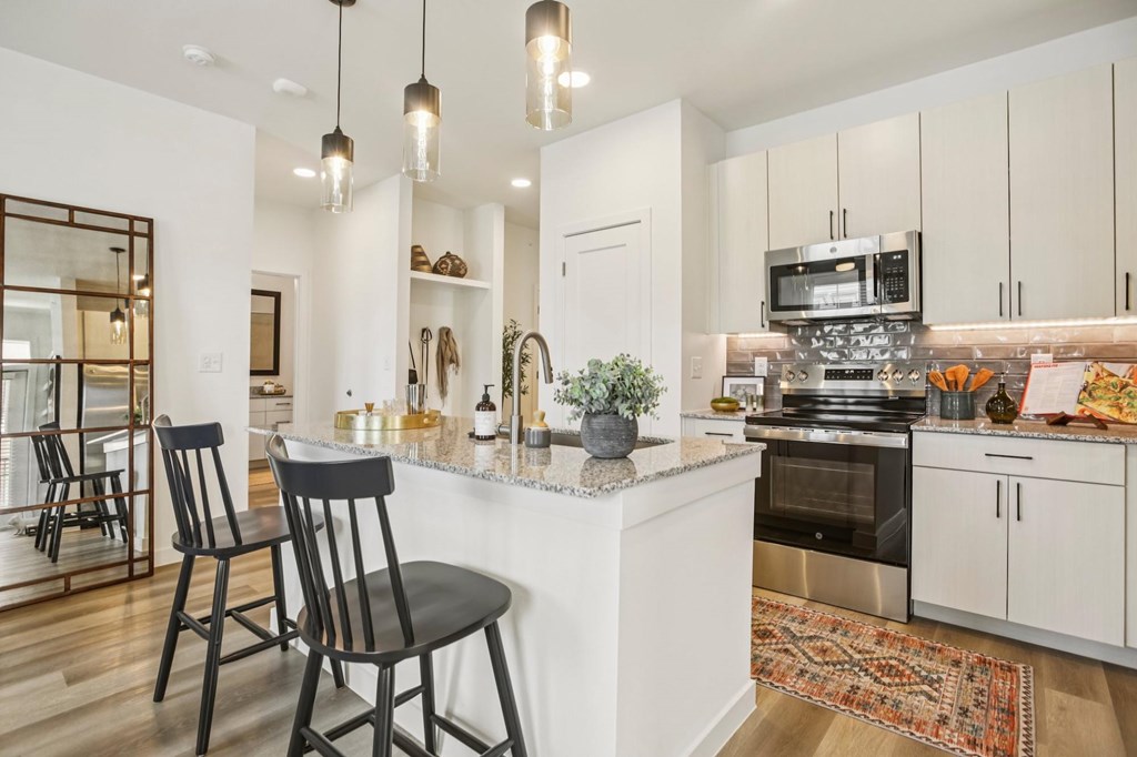 A kitchen with a white countertop and black chairs.