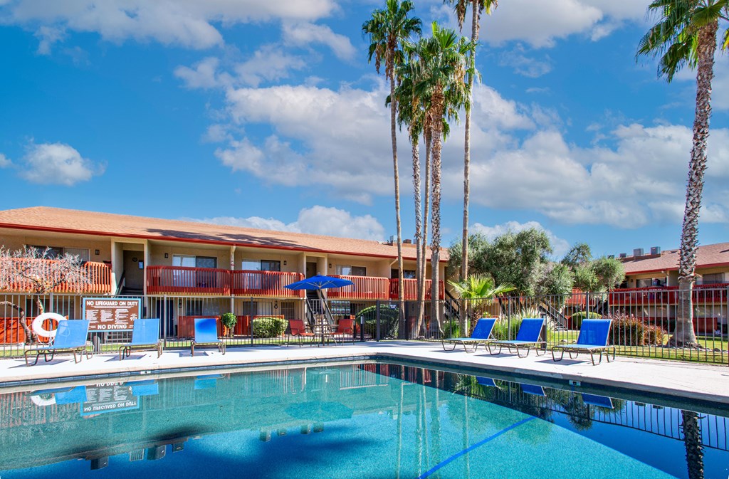 A swimming pool in front of a building with palm trees.
