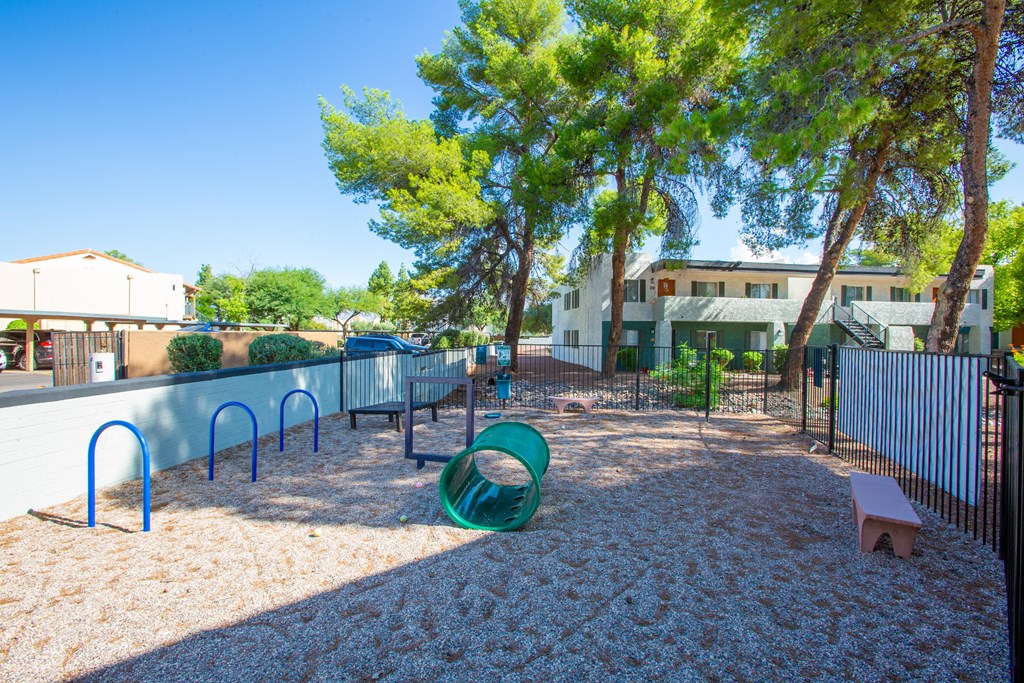 A playground with a green slide and a sandy area.