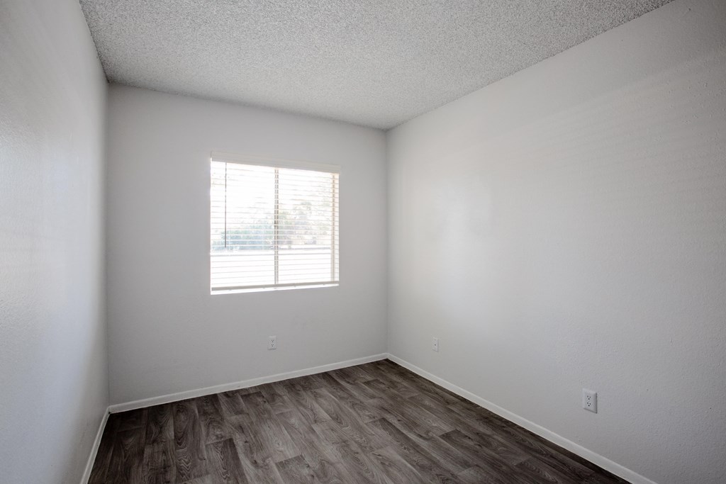 A room with a window and wooden flooring.
