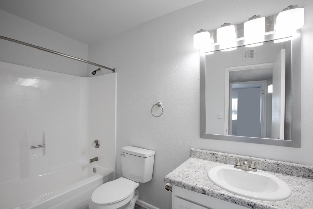 A white bathroom with a toilet, sink, and mirror.