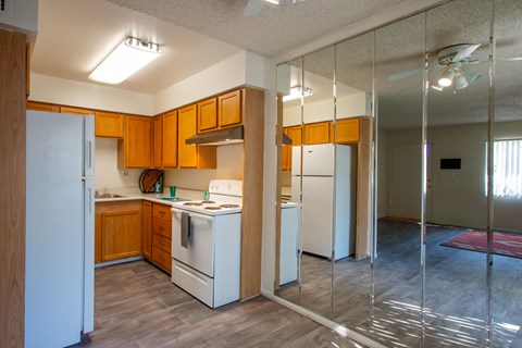 A kitchen with a white refrigerator and wooden cabinets.