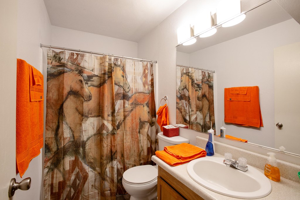 A bathroom with a horse print shower curtain.