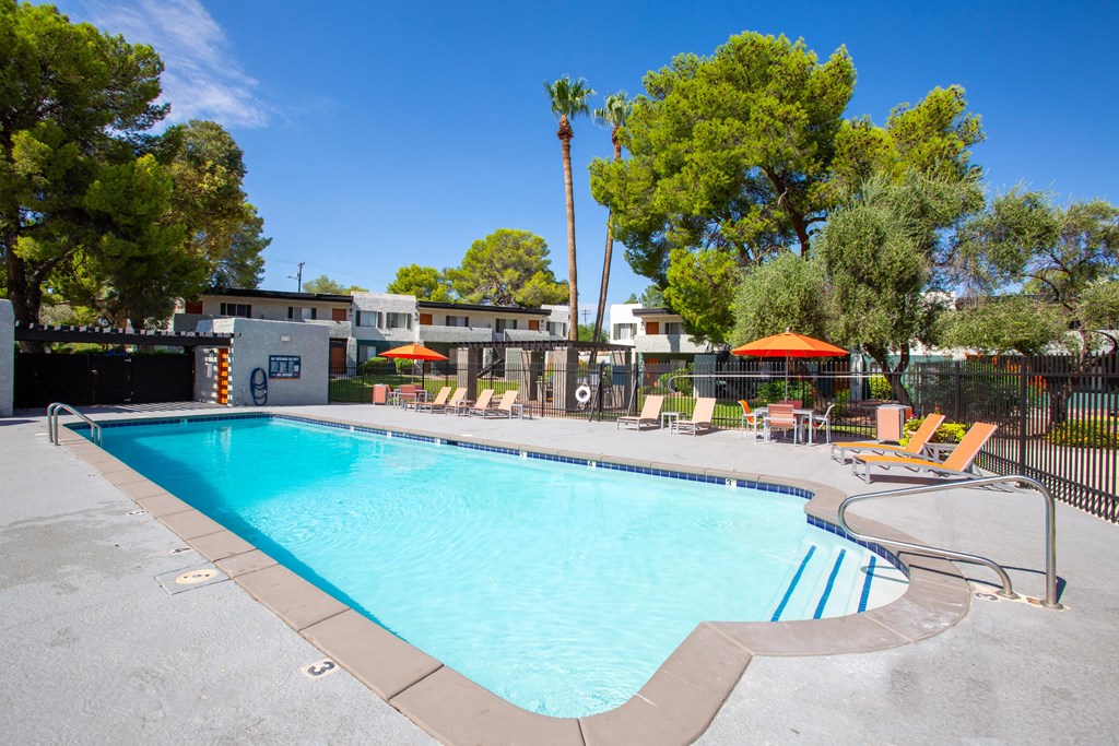 A large swimming pool surrounded by trees and chairs.