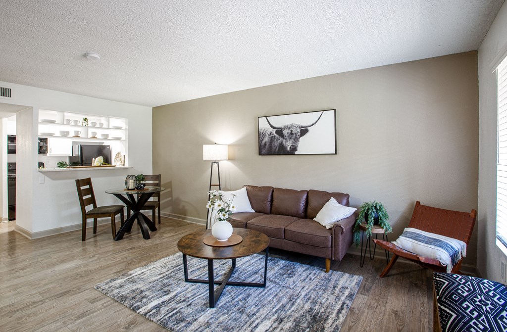 A living room with a brown couch, a coffee table, and a painting on the wall.