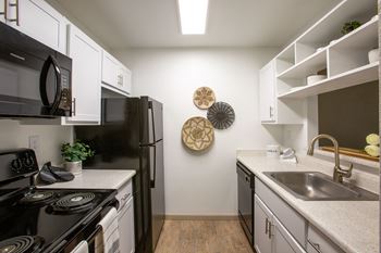 A kitchen with black appliances and white cabinets.