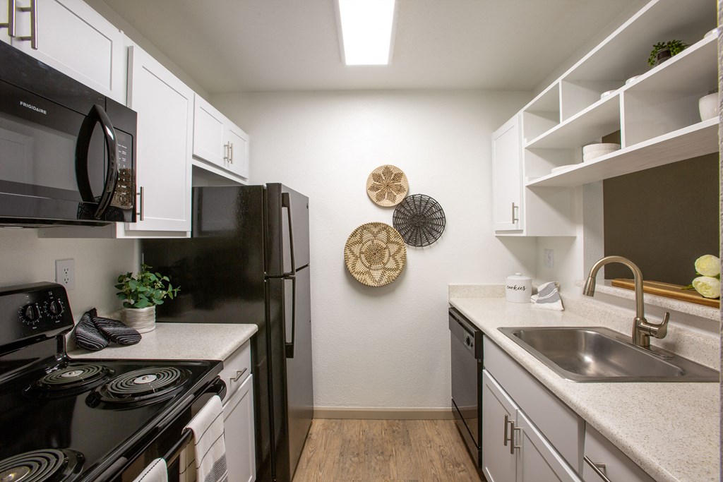 A kitchen with black appliances and white cabinets.