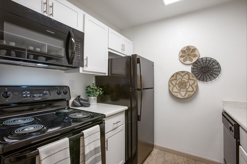 A black stove top oven with a white counter top and a black refrigerator in a kitchen.
