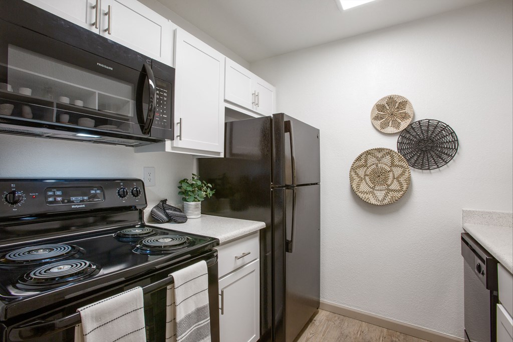 A black stove top oven with a white counter top and a black refrigerator in a kitchen.