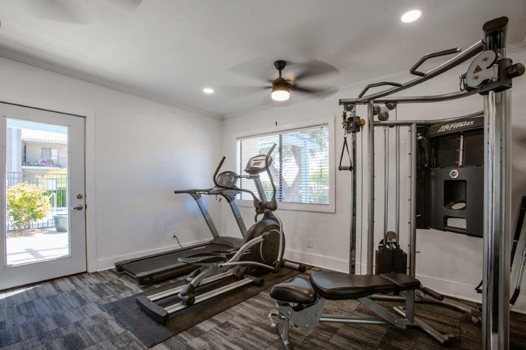 A home gym with a treadmill, elliptical trainer, and other exercise equipment.