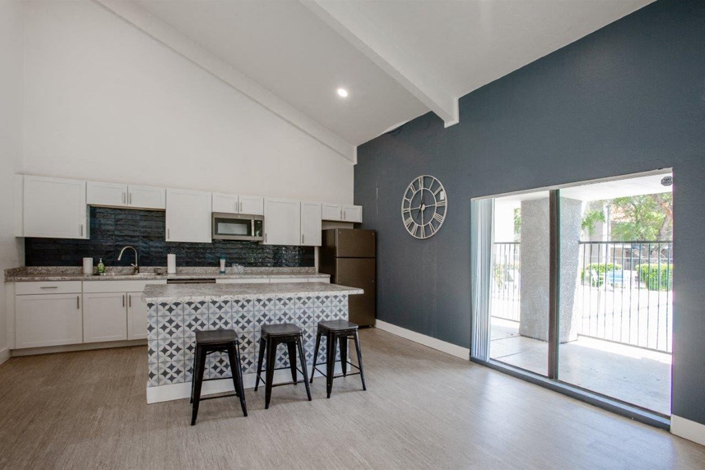 A kitchen with a bar stool and a clock on the wall.