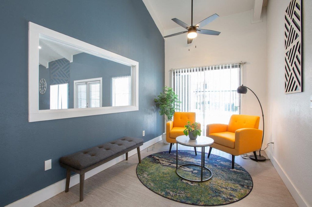 A living room with a blue wall and a mirror.