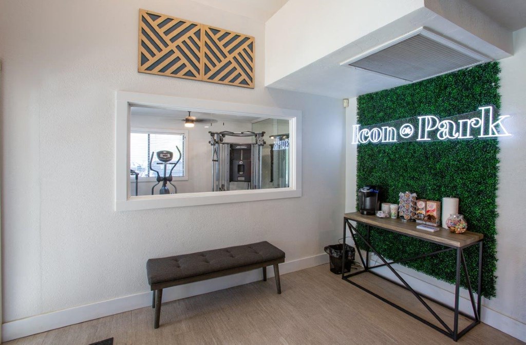 A room with a bench, a mirror, and a green wall with a neon sign that says "Ion Park".