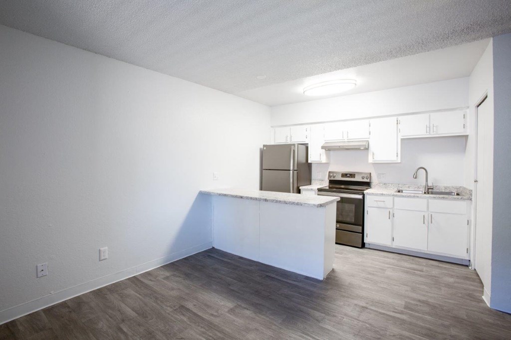 A kitchen with white cabinets and a wooden floor.