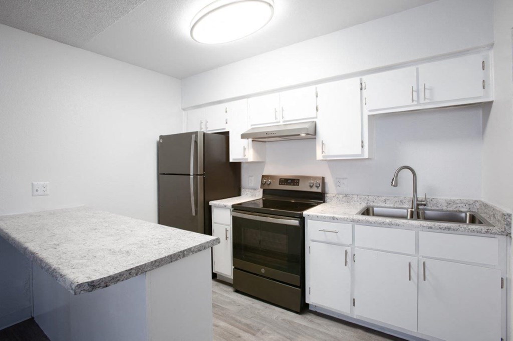 A kitchen with a refrigerator, oven, and sink.