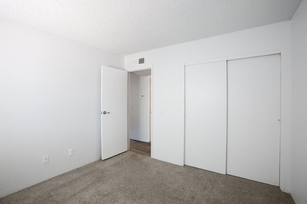 A room with a carpeted floor and three doors.
