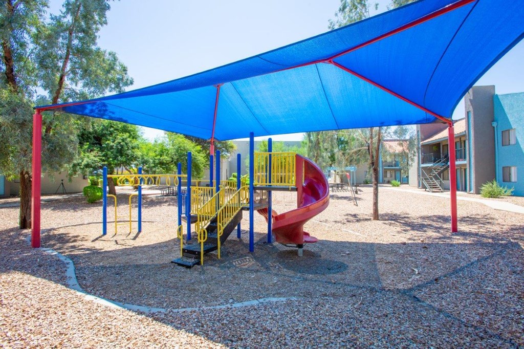 A playground with a blue canopy and a red slide.