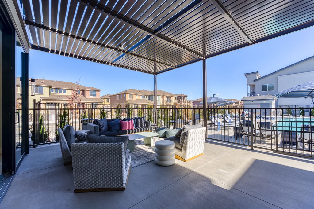 a patio with couches and tables on a balcony with a pool