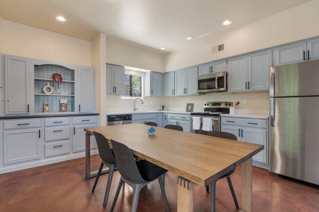 A kitchen with a table and chairs in the foreground and a refrigerator in the background.