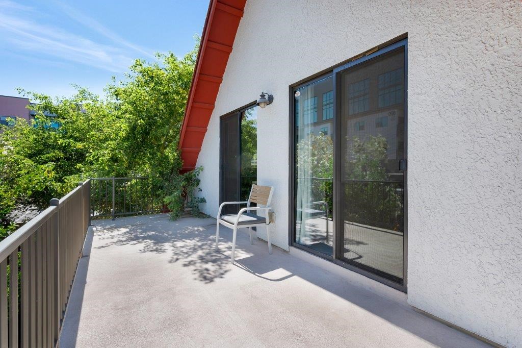 A patio with a chair and a table is on the balcony of a house.