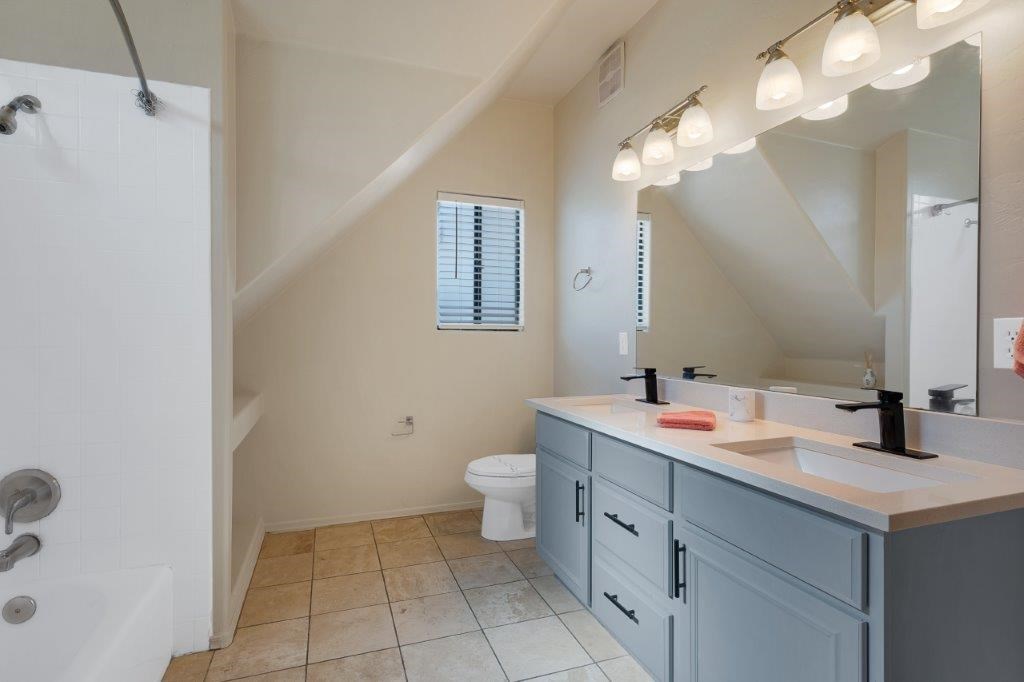 A bathroom with a toilet, sink, and mirror.