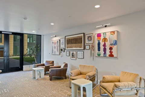 A living room with a variety of chairs and artwork on the wall.